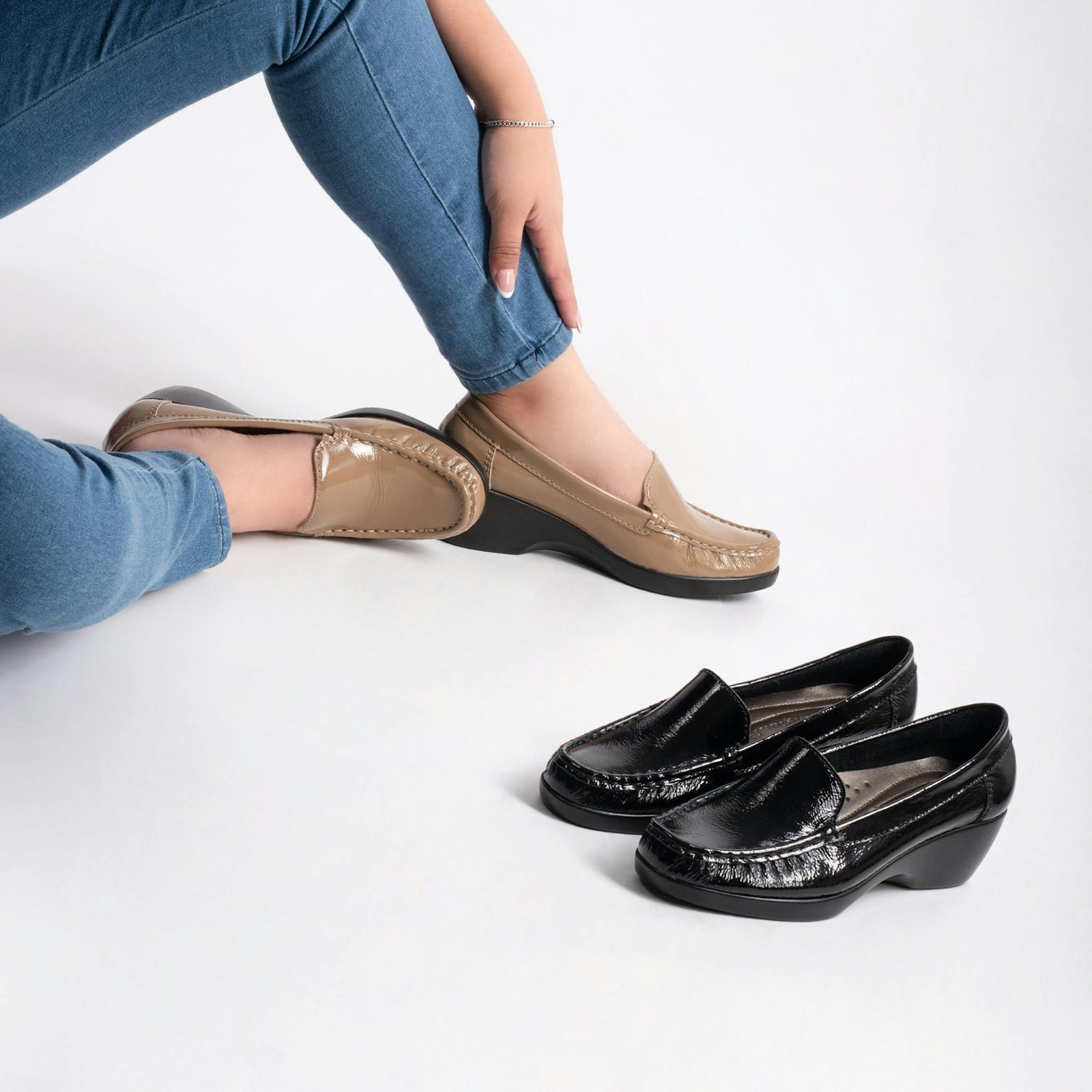 Elegant pair of beige and black moccasins in a studio setting with a model.