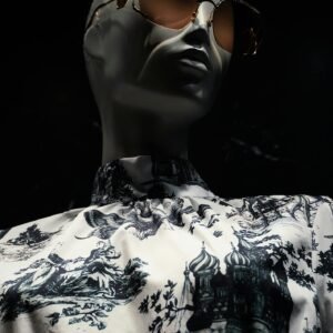 Fashionable mannequin wearing sunglasses and printed shirt on dark background.